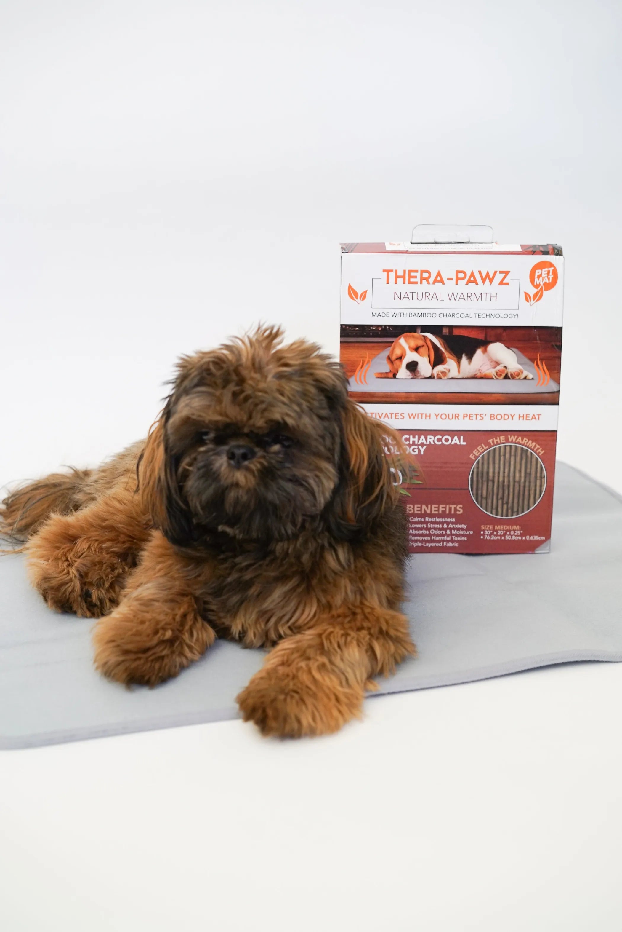 Dog lying on a gray mat with a Thera-Pawz box in the background