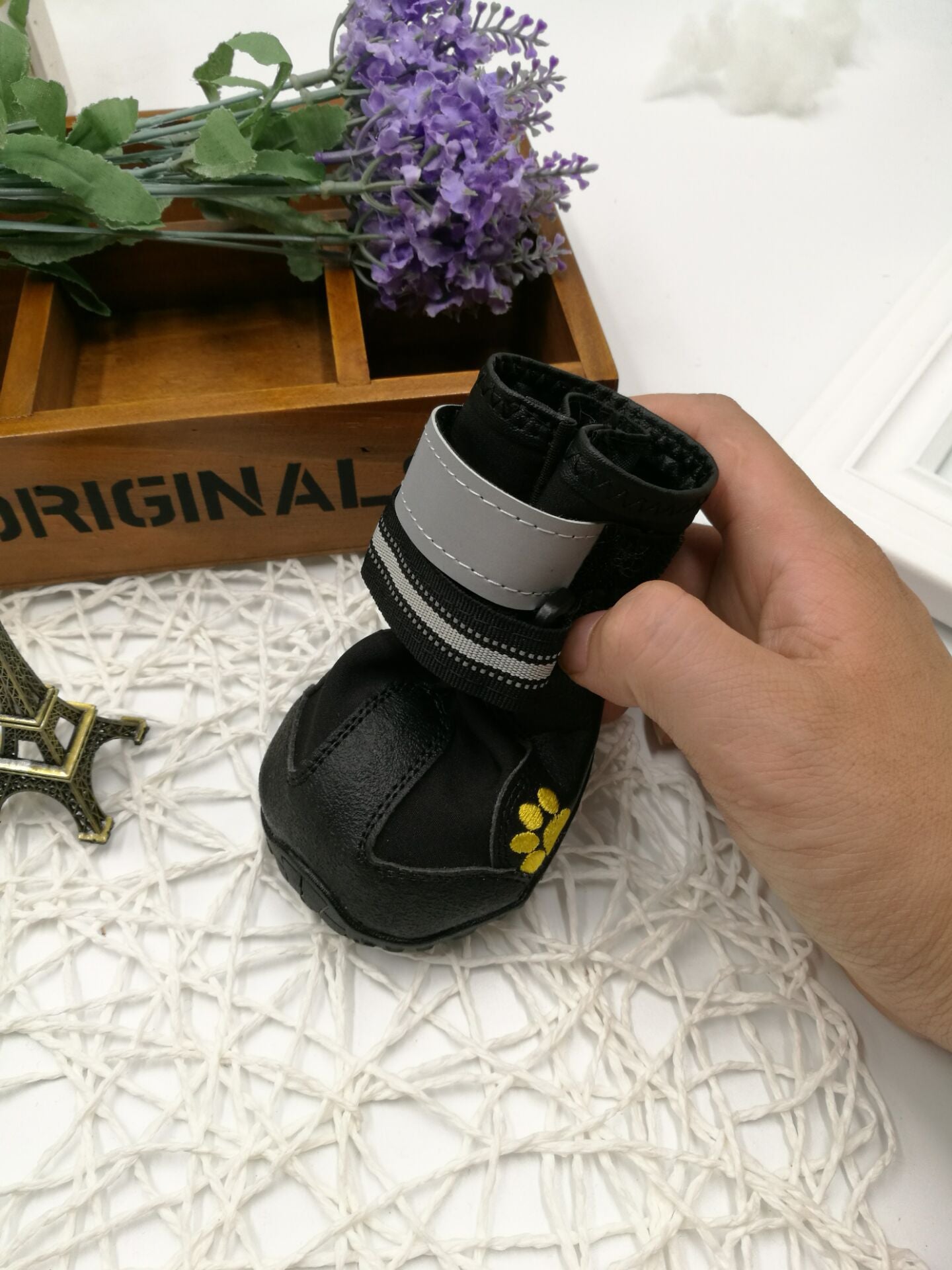 Black pet boots with gray straps held by a hand