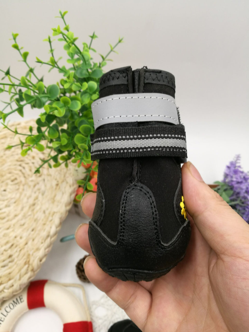 Black pet boot with gray strap held by a hand 