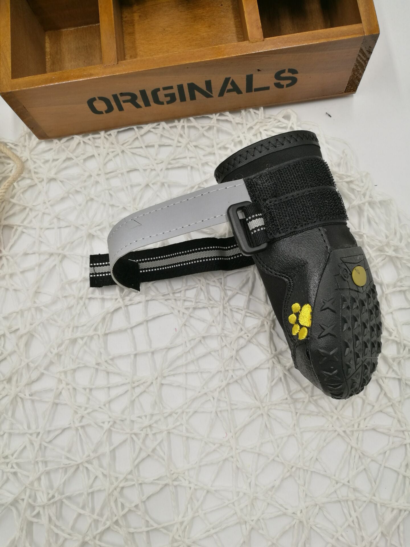 Black dog boot on its side showing a gray strap