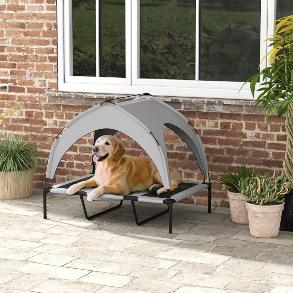 Dog lying on a portable pet bed with canopy in an outdoor setting